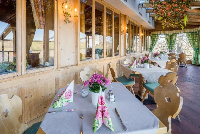 Eingedeckter Wintergarten mit rosa Tischblumen.